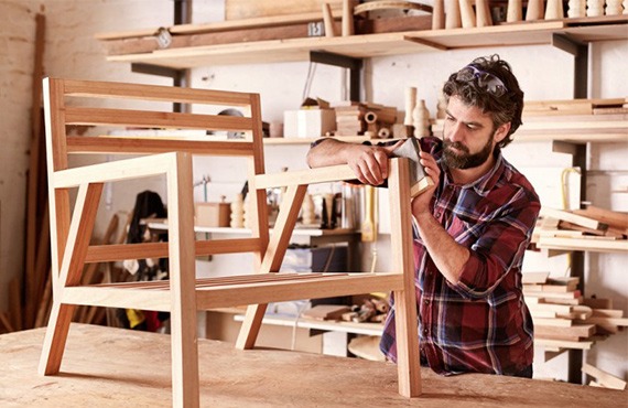 Handwerker arbeitet an einem Holzstuhl im Workshop.